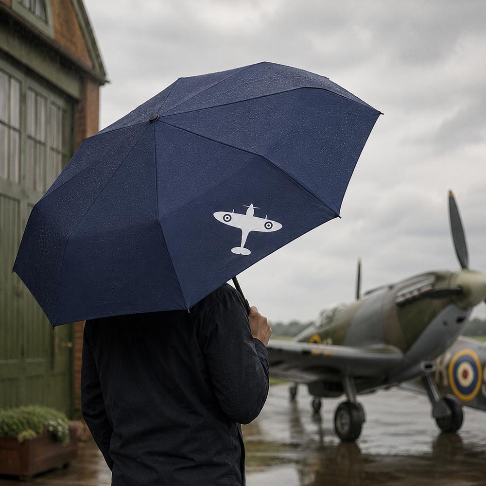 Navy blue folding umbrella featuring a white Spitfire silhouette, with a compact black handle and wrist strap.